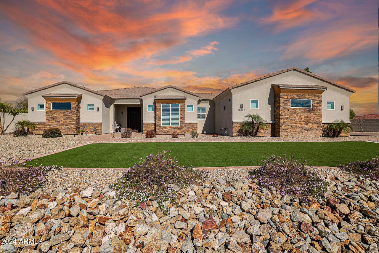 Montebello Court custom home with stone accents, desert landscaping and a sunset sky